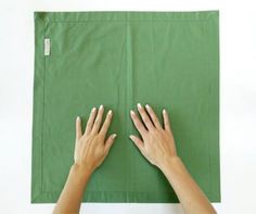 two hands on top of a green piece of paper