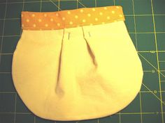 a white purse sitting on top of a cutting board next to a green mat with yellow polka dots