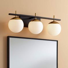 three lights are hanging on the wall above a mirror