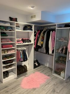 an organized closet with clothes, shoes and other items on shelves in the center of the room