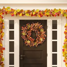 a front door decorated with fall leaves and a wreath