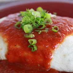 a red plate topped with meat covered in sauce