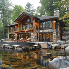 a large house sitting on top of a lush green hillside next to a river filled with rocks