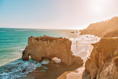 the sun shines brightly on an ocean beach with cliffs and people in the water