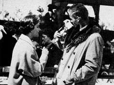 an old black and white photo of two people talking to each other in front of a crowd