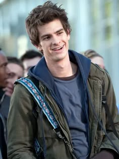 a young man with a butterfly on his shoulder smiles at the camera while standing in front of a group of people