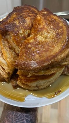 a stack of pancakes sitting on top of a white plate next to a person's arm