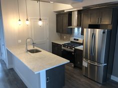 an empty kitchen with stainless steel appliances and dark wood cabinets, along with white countertops