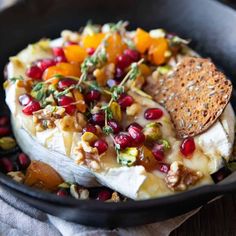 a pan filled with fruit and bread on top of a wooden table next to a napkin