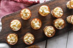 small cups filled with food sitting on top of a wooden cutting board