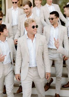 a group of men in white suits and sunglasses standing on steps with one man giving the peace sign