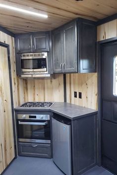 an empty kitchen with wood paneling on the walls and floor, including a stove top oven