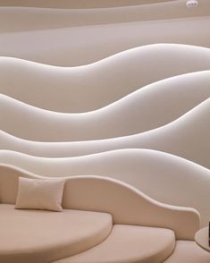 a white couch sitting in front of a wall with wavy lines on it's sides