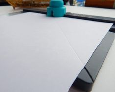 a close up of a white paper on a table with a blue object in the background