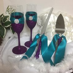 three wine glasses decorated with purple and teal glitters, one is holding a knife