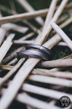 two wedding bands sitting on top of each other in front of some sticks and grass