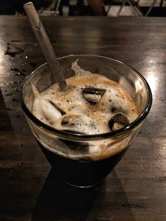 a glass filled with liquid sitting on top of a wooden table next to a knife