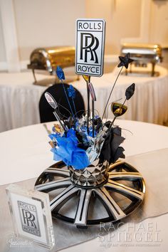 an arrangement of flowers in a vase on top of a table with rolls and royce sign