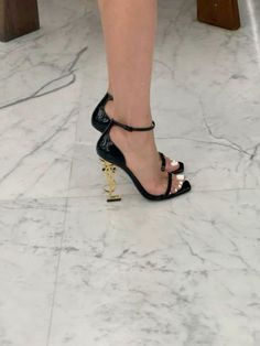 a woman's legs in high heels on the floor with marble floors and walls