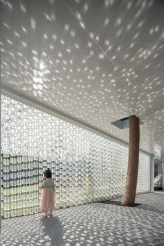 a woman standing in front of a white building with lots of glass covering it's walls