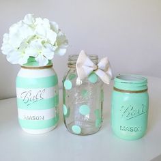 three jars with flowers in them sitting on a table