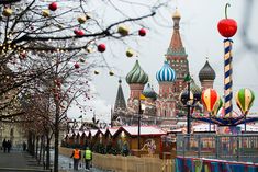 people are walking down the street in front of some buildings with christmas decorations on them