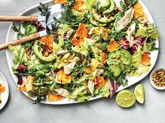 a salad with chicken, lettuce and avocado on a white plate