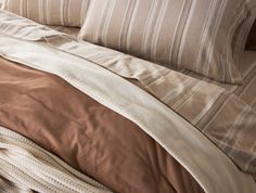 an unmade bed with brown and white sheets