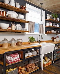 a kitchen filled with lots of open shelves next to a white sink and counter top