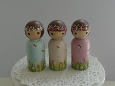 three small wooden dolls sitting on top of a white doily