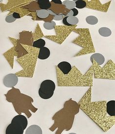 gold and black confetti cutouts are scattered on a white surface with circles