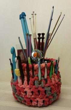 a crocheted basket with pens, scissors and other items in it sitting on a table