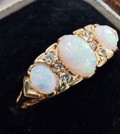 An attractive, vintage, opal and diamond ring, in a carved half-hoop setting, set with 3 oval cabochon-cut opals, with 6 single-cut diamonds set in between. With full British hallmarks dating the ring to 1977.Hallmarked as 18ct gold, dated London 1977.Maker's mark "J&P" for "Joseph & Pearce".The width of the head of the ring measures approximately 6.6mm.The approximate weight is 4.2 grams.Please note that the antique ring box pictured is for display purposes only. Thank you.Ring size M ( Oval Three Stone Opal Ring Fine Jewelry, Classic Three Stone Oval Opal Ring, Opal And Diamond Ring, Antique Ring Box, Opal Diamond Ring, Antique Ring, Small Rings, Maker's Mark, Diamond Cluster Ring