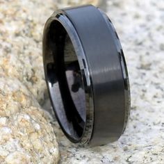 a black ceramic ring with an antler wood inlay on the inside is resting on a rock