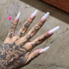 a person's hand with white nails and tattoos on it