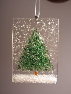 a glass ornament with a small christmas tree in the center and snow around it