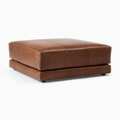 a brown leather ottoman sitting on top of a white floor