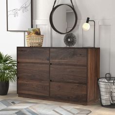 a wooden dresser sitting next to a mirror on top of a white wall in a living room