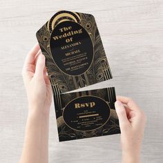 a person holding up a black and gold wedding card with the words, the wedding art deco