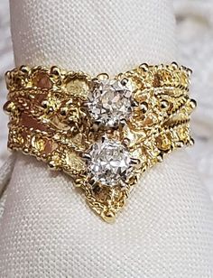 a close up of a ring on a white cloth with gold rings and diamonds in the middle