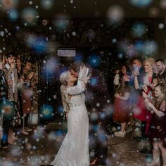 a bride and groom kissing on the dance floor surrounded by bubbles at their wedding reception