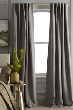 a bed room with a neatly made bed and a window covered in gray drapes