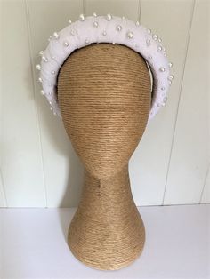 a white hat with pearls on it sitting on top of a mannequin head