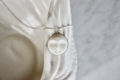 A gorgeous full moon open eye face necklace, so dainty and refined. Every moon cabochon (20mm) is hand-carved, so every little man in the moon will look slightly different. Set in a sterling silver setting and suspended from delicate sterling silver chain. Each cabochon is carved in Bali by the best Balinese master craftsmen and has extremely fine detail. Wonderful bohemian, effortlessly chic.  Wear it on its own or layer it with other necklaces. Model wears a 22" length. Made using the highest Carved White Sterling Silver Necklaces, White Pendant Necklace With Sun And Moon Design, White Round Necklace With Sun And Moon Design, Handmade White Moon-shaped Necklace, Handmade White Moon Shaped Necklace, White Sun And Moon Design Round Necklace, White Jewelry With Sun And Moon Design Gift, White Round Pendant Necklace With Moon Phase, Handmade White Celestial Jewelry