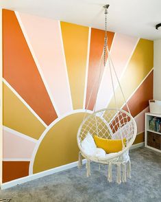 a hanging chair in front of a colorful wall