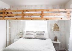 a bedroom with bunk beds and pillows on top of it, in front of a window