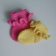 two crocheted baby booties sitting next to each other on a white surface