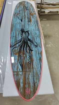 an octopus painted on the side of a surfboard in a store display case,