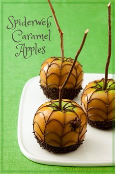 three caramel apples on a white plate with spider web decorations and sprinkles