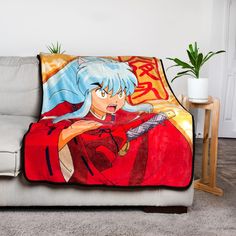 a couch with a blanket on top of it that has an anime character drawn on it